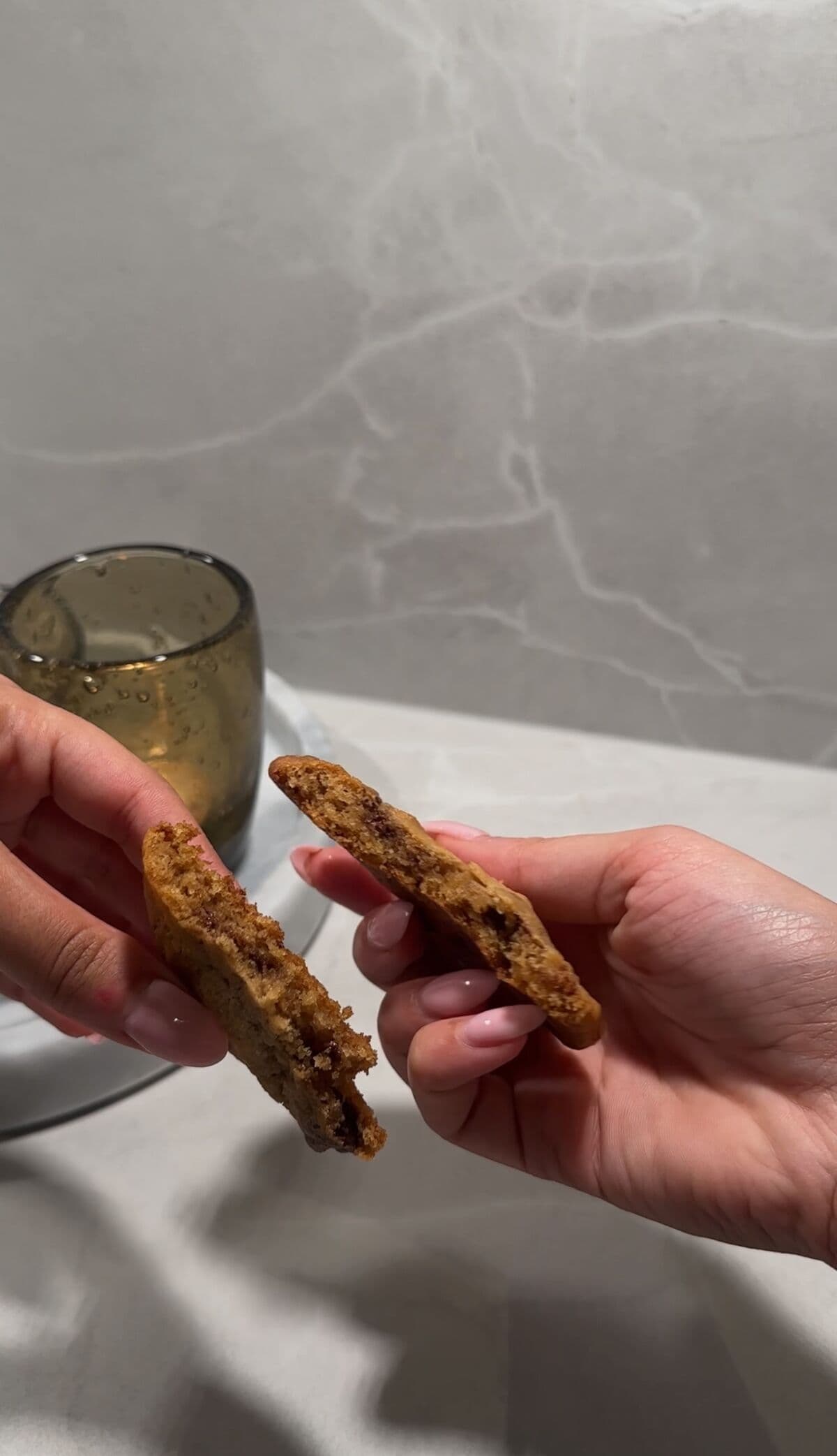 Hender som bryter en nystekt sjokoladecookie i to